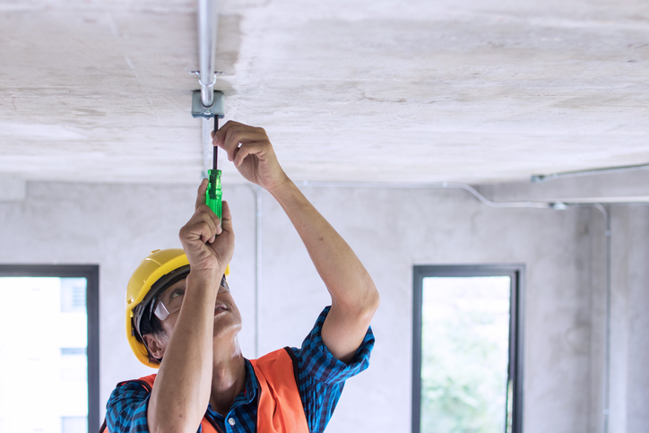 Electrician wiring on ceiling in construction site